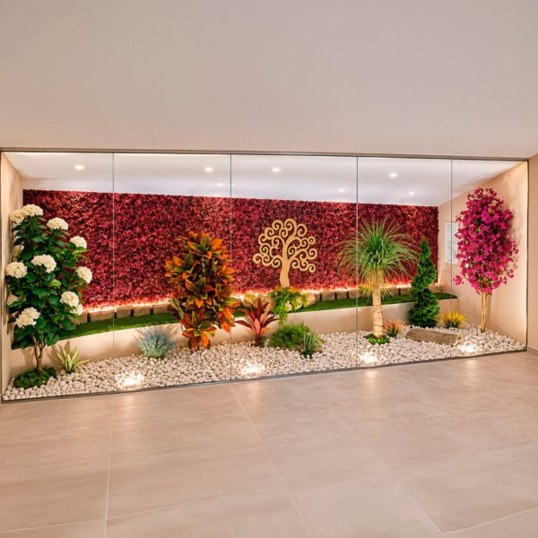 Jardín artificial de interior tras una cristalera, con muro vegetal granate y árbol de la vida